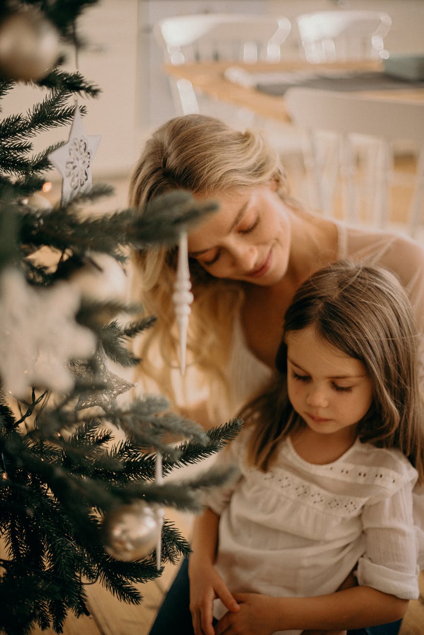 mother and child celebrating family beside Christmas tree